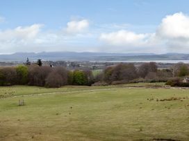 A landscape with grass and trees under a cloudy sky at Kilninver Chalet