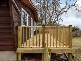 A deck area with wooden railing and flooring at Kilninver Chalet