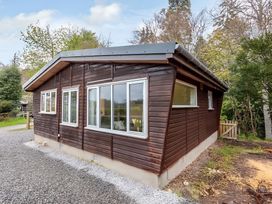 A wooden house with multiple windows and a gravel driveway