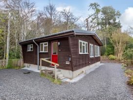 A wooden house with a red door and gravel pathway at the property in an outdoor setting