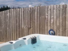 A hot tub with water next to a wooden fence at Old Highwood Barns Dunkeswell