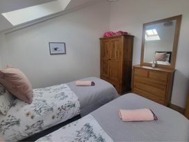 A bedroom with two beds and a wardrobe at Old Highwood Barns in Dunkeswell