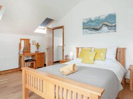 A bedroom with a bed, table, and mirror near a window at The Old Barn in Manchester