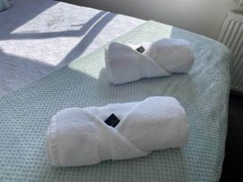 Two rolled towels on a bed in a bedroom