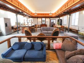 A living room with various seating and a kitchen area at Capel Llani in Llanidloes