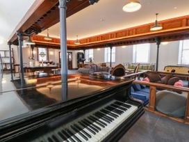 A living room featuring a piano and seating arrangements at Capel Llani in Llanidloes