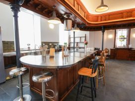 A kitchen with an island and stools at Capel Llani in Llanidloes