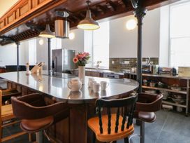 A kitchen with an island and bar stools at Capel Llani in Llanidloes