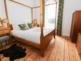 A bedroom with a four-poster bed and wooden furniture at Capel Llani in Llanidloes