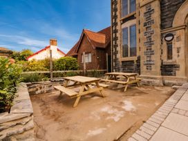 A garden area with benches and tables at Capel Llani in Llanidloes