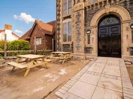 A building entrance with picnic tables and a stone wall at Capel Llani Llanidloes