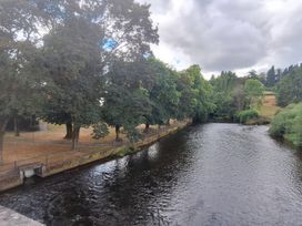 A river with trees and a path beside it at Capel Llani in Llanidloes