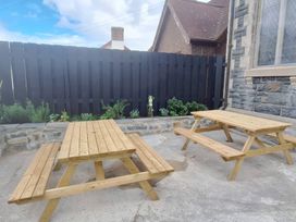 An outdoor area with wooden tables and decorative plants at Capel Llani Llanidloes