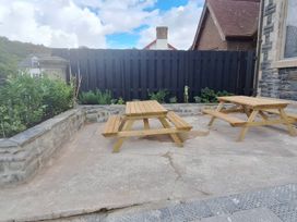 An outdoor area with wooden tables and plants at Capel Llani Llanidloes