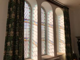 Stained glass windows with curtains in a room at Capel Llani Llanidloes