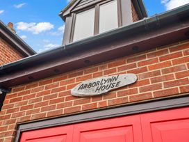 A sign for Arborlynn House on a brick wall with red doors