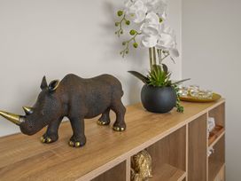 A shelf with a rhino sculpture and a plant at a property