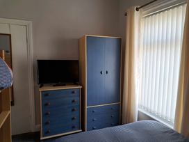 A bedroom with a television and wardrobe at Fisherman's Cottage
