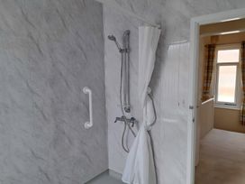 A shower area with a curtain and door at Fisherman's Cottage