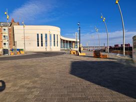 A waterfront area with a building and benches at Fisherman's Cottage 