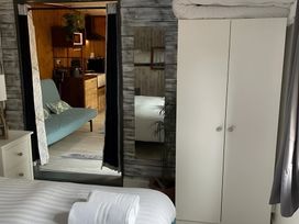 A bedroom with a bed and a wardrobe showing an open doorway to a kitchenette at Little Russets
