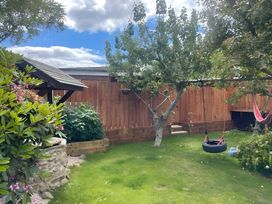 A garden with grass and a swing at Little Russets