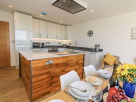 A kitchen featuring an island and a dining table at Sea Fern House - 36, Poole