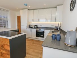 A kitchen with cabinets, a microwave, kettle, and mugs at Sea Fern House - 36 Poole