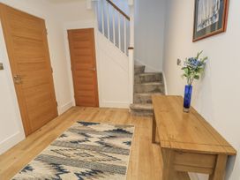 A hallway with stairs and a table with flowers at Sea Fern House - 36 in Poole