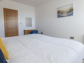 A bedroom with a bed, chair, and wall art at Sea Fern House - 36 Poole