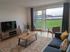 A living room with a television and furniture at Sea Fern House - 36, Poole