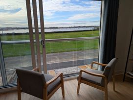 A living room with two chairs and a view of grass and water at Sea Fern House - 36 Poole