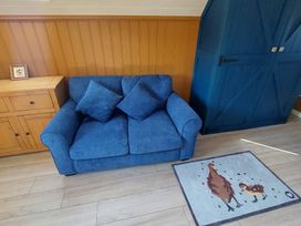 A living room with a blue couch, wooden cabinet, and a rug at the property in location
