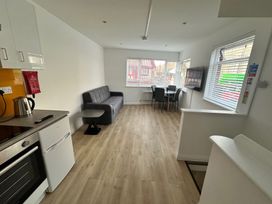 A living room with a sofa and dining area at Red Rose Apartment