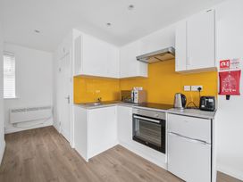 A kitchen with white cabinets and yellow backsplash at Red Rose Apartment in Weymouth
