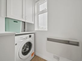 A laundry room with a washing machine and storage cabinet at Red Rose Apartment in Weymouth