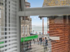 A view from a window showing a street and ocean at Red Rose Apartment in Weymouth
