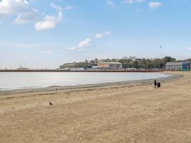 A beach with water and people walking at Red Rose Apartment in Weymouth