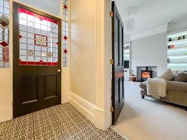 A hallway with a stained glass door and a view of a living room at Victorian Beach House