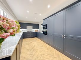 A kitchen with dark cabinets and a white countertop at Victorian Beach House