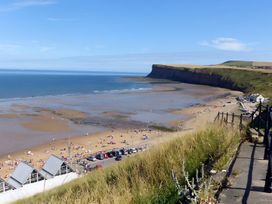 A beach view with a cliff and people at the shoreline at Victorian Beach House