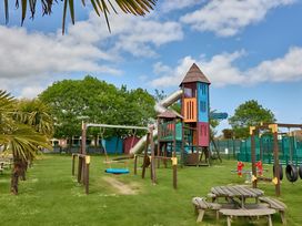 A playground with a slide, play tower, swings and picnic tables at 214 Oaklands Area