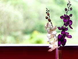 A vase with orchids on a table at Gisburn Forest Lodge