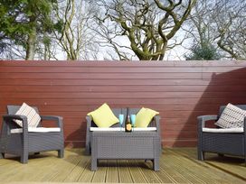 Outdoor seating area with a table and cushions at Gisburn Forest Lodge