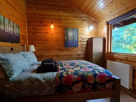 A bedroom with a bed and wardrobe at Gisburn Forest Lodge