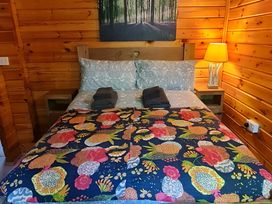 A bedroom with a bed and wooden walls at Gisburn Forest Lodge