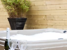 A hot tub with champagne and glasses in an outdoor area at Gisburn Forest Lodge