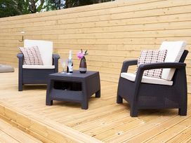 An outdoor seating area with two chairs and a table at Gisburn Forest Lodge