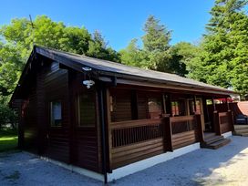 A wooden cabin exterior with a deck and surrounding trees at Gisburn Forest Lodge