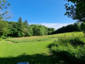A grassy area with trees and a fence at Gisburn Forest Lodge